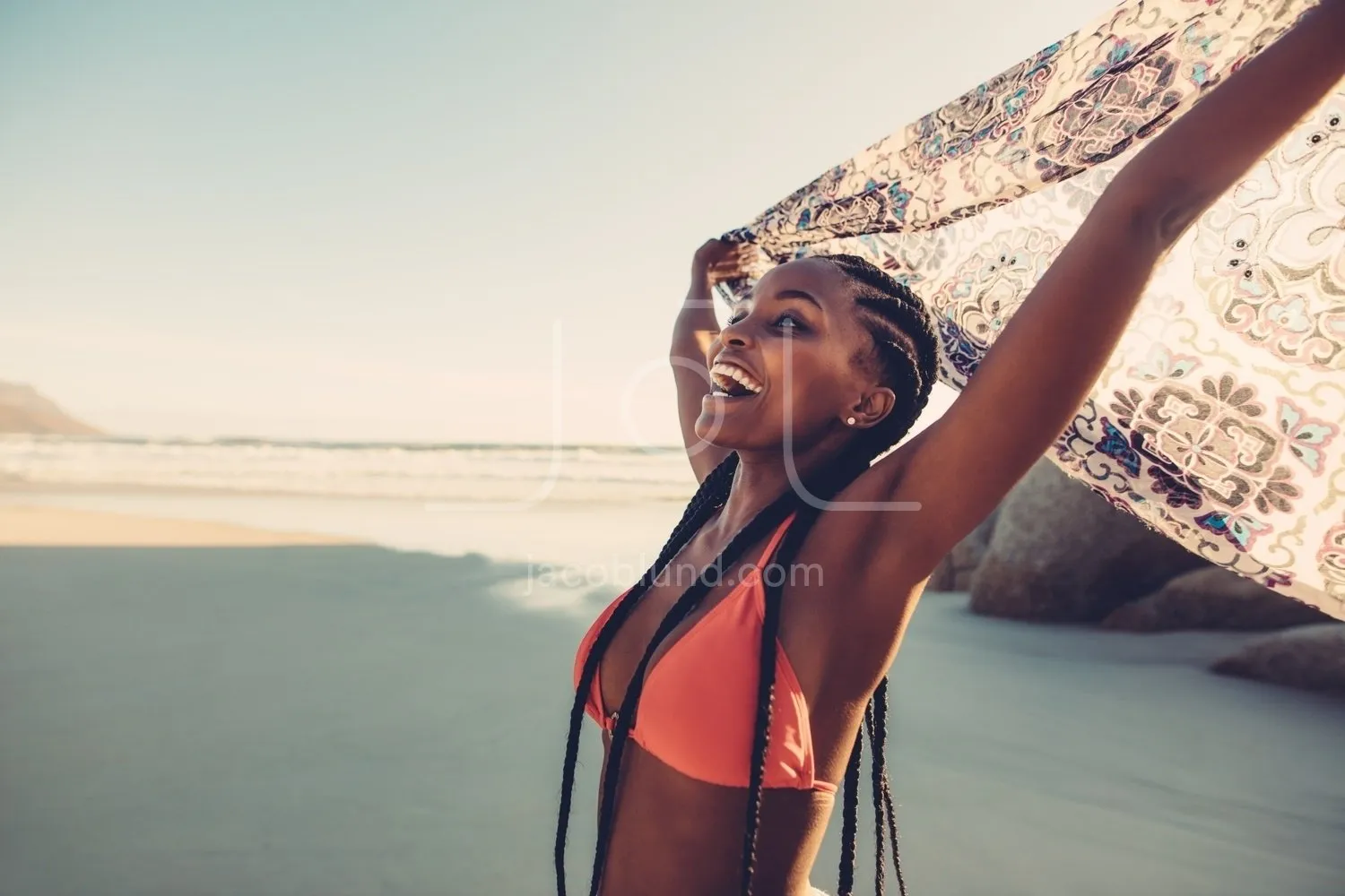 African woman enjoying on the beach with flying scarf